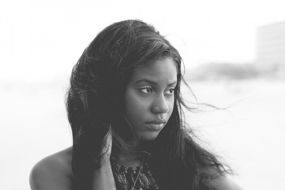 A black woman with long hair looks off to the side.