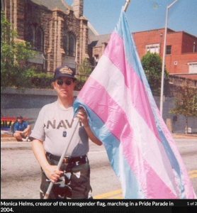 A navy service person holds the transgender flag.